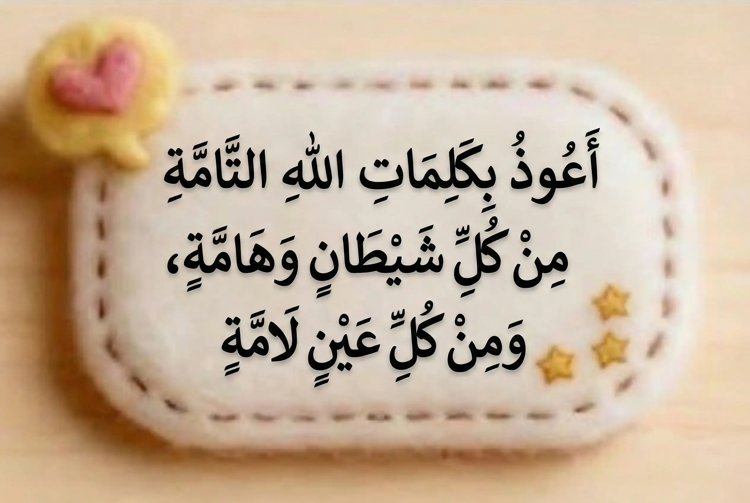 "Clear Arabic calligraphy of the Dua for protection against the Evil Eye (Nazar) written on a soft, cream-colored textured badge. The text reads: A'udhu bi kalimatillahi at-tammati min kulli shaytanin wa hammah (I seek refuge in the perfect words of Allah from every devil and poisonous pest)."